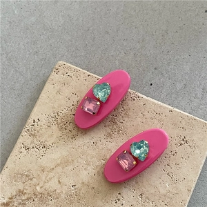 Détail de barrettes ovales rose rouge avec cœur bleu et cristaux rectangulaires violets