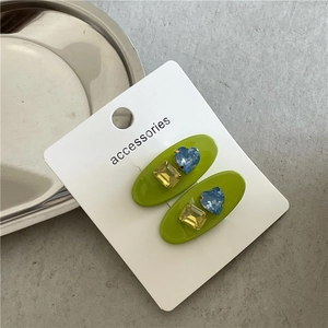 Détail de barrettes vertes ovales avec cœur bleu et strass rectangulaires jaunes
