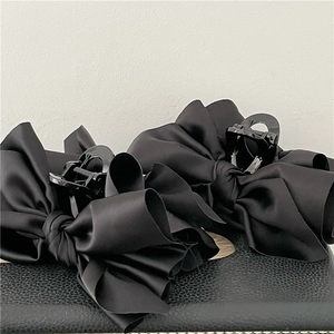 Close-up of elegant black satin bow hair claws with silk texture and sturdy plastic grip