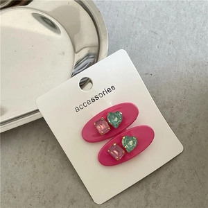 Détail de pinces à cheveux ovales roses avec strass colorés sur carte d'accessoires