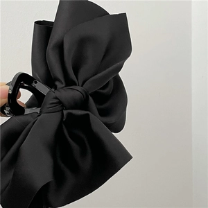 Detail of elegant black satin ribbon bow hair claw clip showing smooth fabric texture