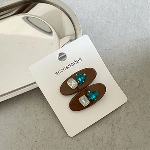 Détail de barrettes ovales marron café avec des strass en forme de cœur sur carte