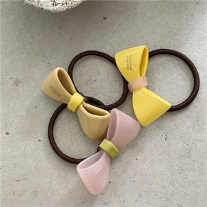 Detaillierte Ansicht von drei farbigen Acetat-Bogen-Haargummis in Gelb, Beige und Rosa