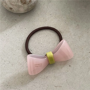 Detailansicht eines rosa Acetat-Bogen-Haargummis mit gelbem Verschluss und Handarbeit