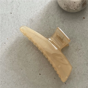 Detailansicht einer geometrischen bernsteinfarbenen Haarklammer mit Marmor-Effekt