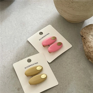 Détail de pinces à cheveux ovales roses et moutarde avec plaques dorées sur carte déco
