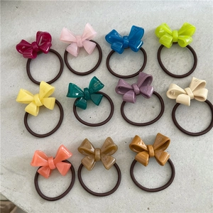 Colorful 11-piece acetate bow hair ties set with high-gloss finish on grey texture