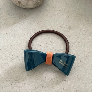 Details des blauen Acetat-Haargummis mit orangefarbenem Kontrast und Goldbeschriftung