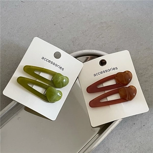 Set of jelly-texture resin heart hair clips in green and brown on a silver tray