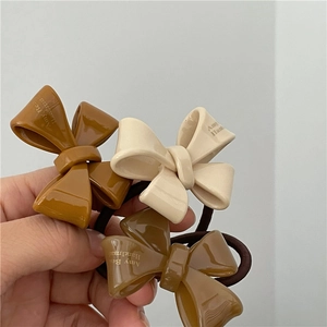 Close-up of premium acetate bow hair ties in earth tones with Amy Belle branding