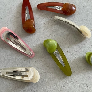 Minimalist jelly heart resin hair clips in various marble colors on a grey stone surface