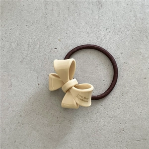 Detail of a beige bow hair tie with Amy Bear Handmade lettering on a gray stone surface
