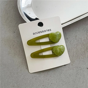 Set of two olive green heart hair clips with marble texture on a display card