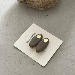 Détail de barrettes ovales moka avec accents dorés sur une surface en pierre texturée