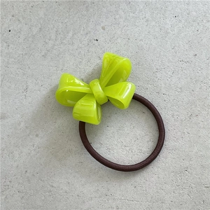 Close-up of a neon green acetate bow hair tie with handmade engraving and elastic band