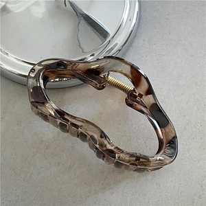 Detail view of leopard print hair claw clip showing amber resin texture and gold spring