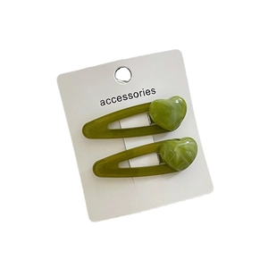 Pair of matcha green heart-shaped hair clips with marble resin texture on white background