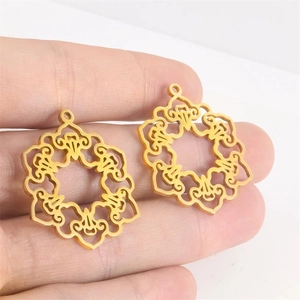 Dettaglio dei ciondoli a fiore geometrici cavi in oro tenuti a mano per scala dimensionale