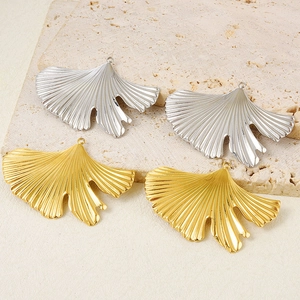 Detailed close-up of gold and silver ginkgo leaf pendants on natural stone texture