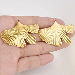 Golden 304 stainless steel ginkgo leaf pendants shown on palm for size reference