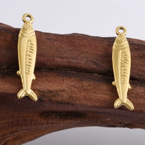Dettaglio di ciondoli a forma di pesce placcati oro 18k con squame su legno rustico