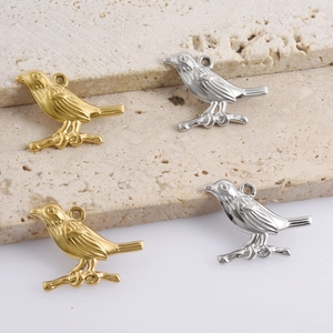 Macro detail of bird on branch pendants in polished gold and silver finishes