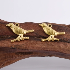 Macro view of detailed golden bird pendants on wood for DIY jewelry making
