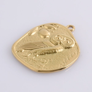Detail view of 18k gold owl pendant with hammered texture and intricate relief design