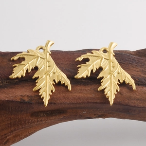 Detailed close-up of 18k gold plated leaf pendants with intricate veins on wood