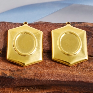 Detail view of two gold hexagon pendant trays on wooden background for DIY jewelry making