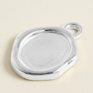 Vue macro d'un support pendentif ovale en acier inoxydable argenté avec texture de sceau cire