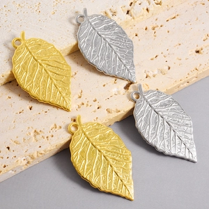 Macro detail of leaf charms in gold and silver finish on stone background