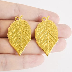 304 stainless steel gold leaf pendants showing realistic texture and size on fingers