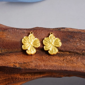 Macro view of golden stainless steel flower pendants with brushed texture on wood