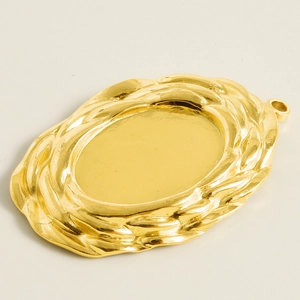 Macro view of gold stainless steel oval charm base with textured wave edge for DIY