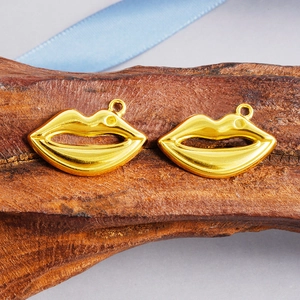 Detail shot of gold-plated lip-shaped pendants on wood texture with blue silk ribbon