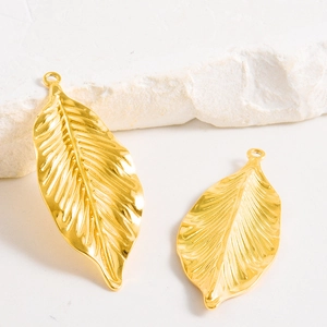Détail macro du pendentif feuille en acier inoxydable plaqué or avec nervures fines