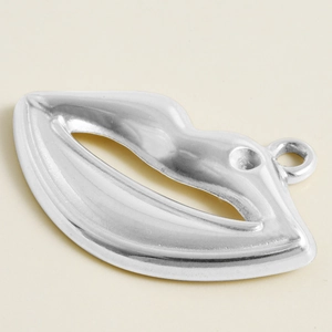 Macro detail of silver stainless steel lip-shaped pendant with polished metallic surface