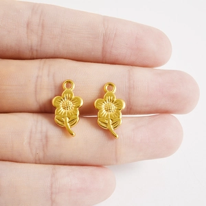 Détails de pendentifs fleurs en acier doré montrant les pétales ciselés et les feuilles