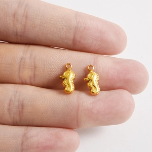 Vue macro d'un petit pendentif hippocampe doré sur le bout du doigt pour l'échelle