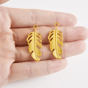 Détail des pendentifs feuilles dorées avec texture évidée délicate dans la main