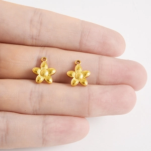 Gros plan de pendentifs fleurs dorées en acier inoxydable 304 avec cœur texturé pour DIY