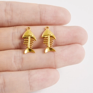 Vue macro détaillée de deux pendentifs arêtes de poisson dorés en acier inoxydable 304