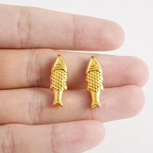 Gros plan de petits pendentifs poissons dorés en acier inoxydable 304 pour bijoux DIY