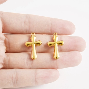 Polished 18K gold-plated 304 stainless steel cross pendants held by hand for DIY jewelry