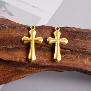 Macro shot of two 18K gold plated stainless steel cross pendants on a wooden base