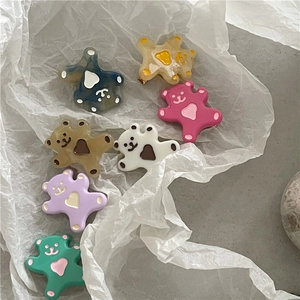 Détails de sept pinces à cheveux en forme d'ours colorés sur un fond de papier blanc texturé