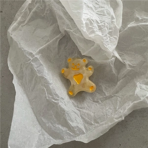 Gros plan d'une pince à cheveux ours avec cœur jaune et texture en résine marbrée