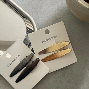 Détail de barrettes à cheveux feuille de saule en métal brossé doré et noir sur carte