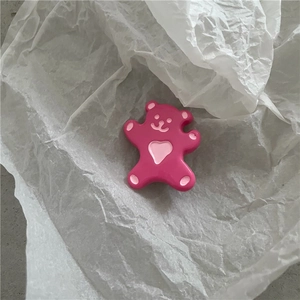 Détail d'une mignonne pince à cheveux ours rose avec cœur sur un fond de papier blanc